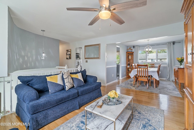 living area with wood finished floors, a ceiling fan, a chandelier, and baseboards