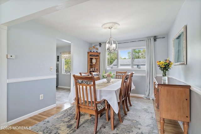 dining area featuring a chandelier, plenty of natural light, baseboards, and light wood-style flooring