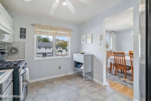 kitchen featuring stainless steel range with gas stovetop, ceiling fan, white cabinetry, baseboards, and light countertops