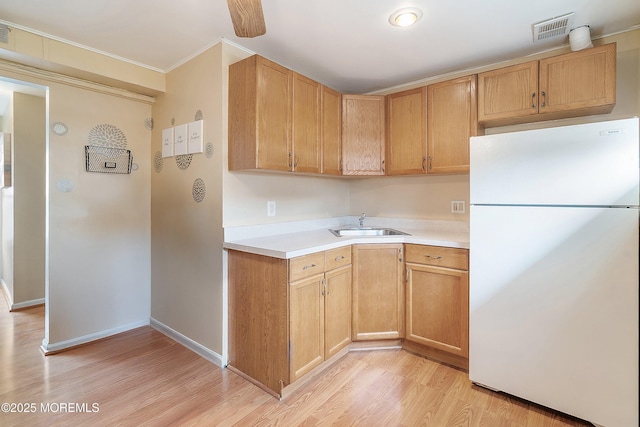 kitchen with freestanding refrigerator, light countertops, light wood finished floors, ornamental molding, and baseboards
