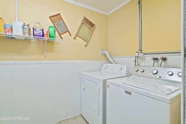 laundry room with crown molding, washing machine and dryer, and light tile patterned floors
