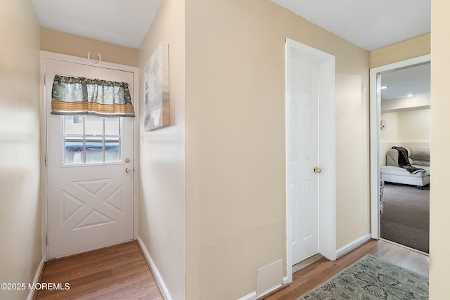 corridor with light wood-type flooring and baseboards