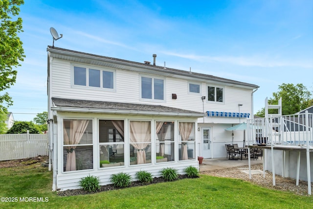 rear view of house featuring a wooden deck, a patio, a shingled roof, and a sunroom