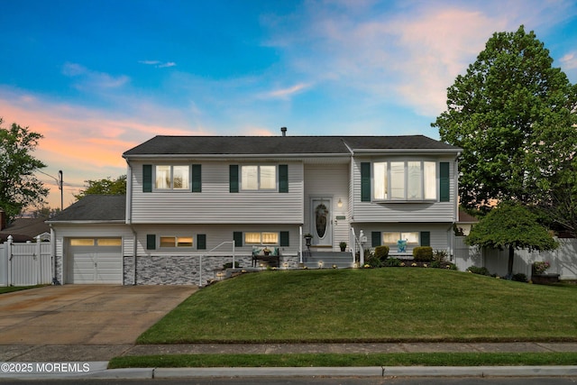 split foyer home featuring an attached garage, concrete driveway, and stone siding