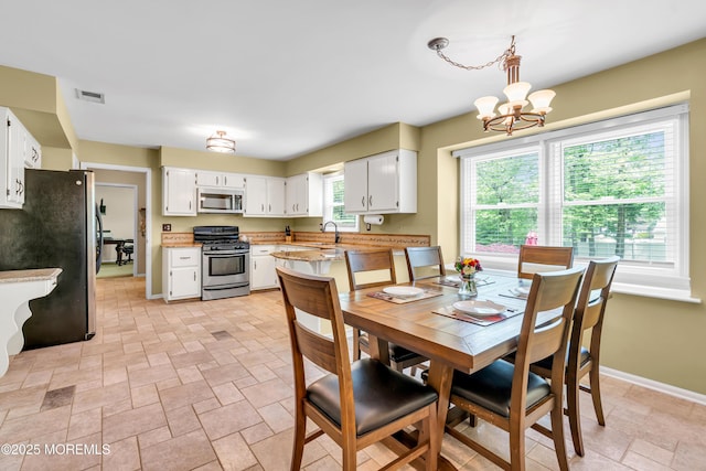 dining area with light stone finish flooring, a chandelier, and baseboards