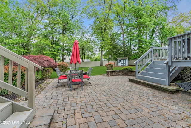 view of patio featuring a shed, an outbuilding, outdoor dining area, a wooden deck, and stairs