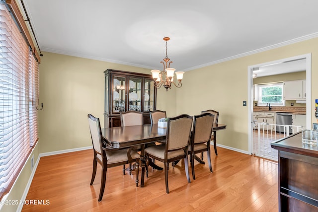 dining space with light wood-style flooring, a chandelier, ornamental molding, and baseboards