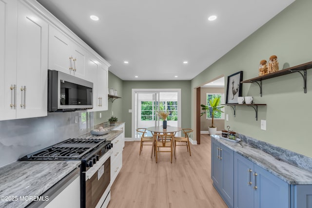 6 Reef Pl, Brick, NJ 08723 - kitchen with stainless steel microwave, gas range oven, blue cabinetry, open shelves, and light wood-style floors