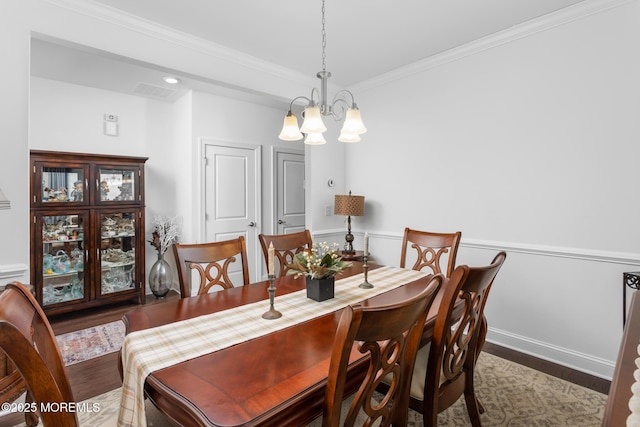dining area with wood finished floors, a chandelier, crown molding, and baseboards