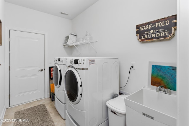 clothes washing area featuring washer and clothes dryer and light tile patterned flooring