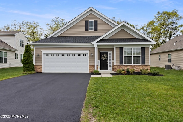 view of front facade featuring driveway, a front yard, a garage, and stone siding