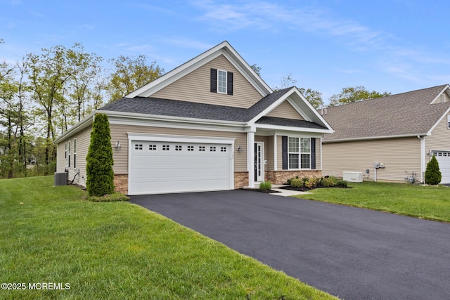 view of front of house featuring asphalt driveway, a garage, cooling unit, and a front yard