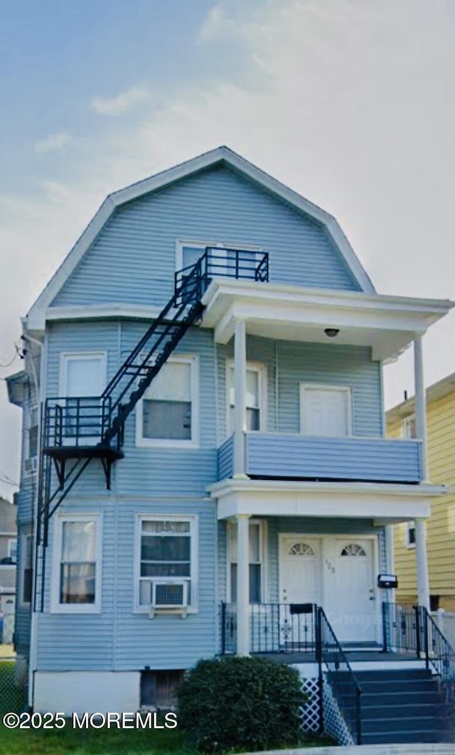 view of front of property featuring stairway, a balcony, a porch, and a gambrel roof