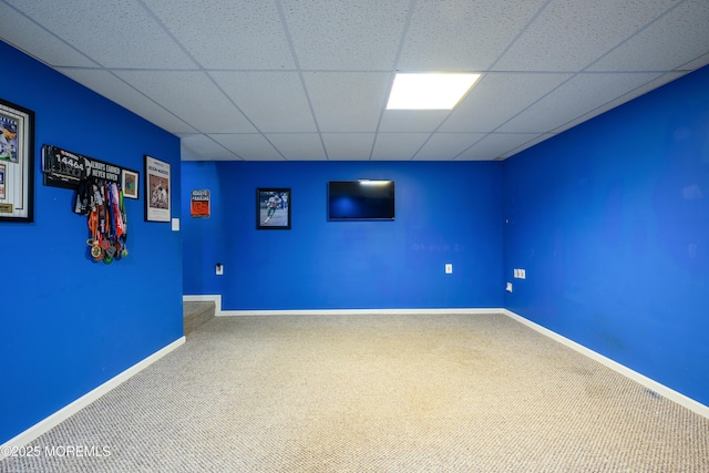 carpeted spare room featuring baseboards and a drop ceiling