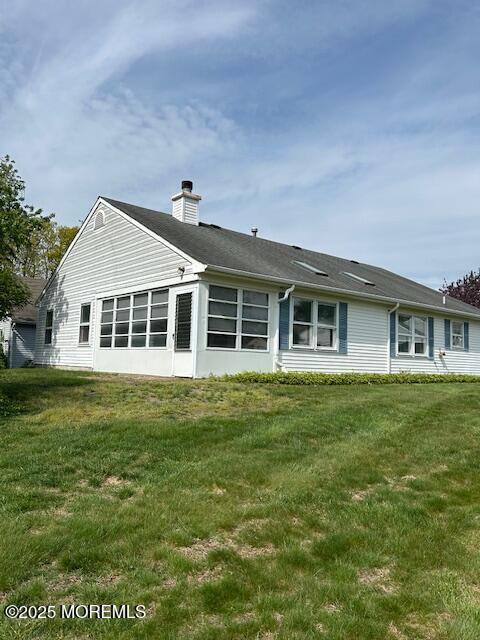 back of property with a lawn and a chimney