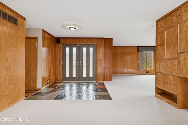 foyer with wooden walls, stone finish floors, and baseboards