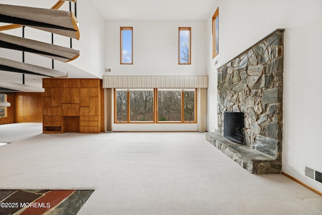 unfurnished living room featuring a fireplace, a high ceiling, and carpet floors