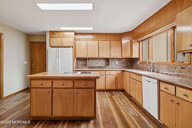 kitchen featuring white appliances, a sink, wood finished floors, a center island, and tasteful backsplash