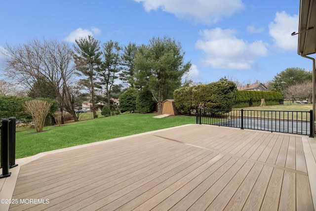 wooden terrace featuring a shed, an outbuilding, and a yard