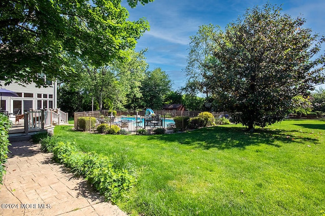 view of yard with a fenced in pool, fence, and a wooden deck