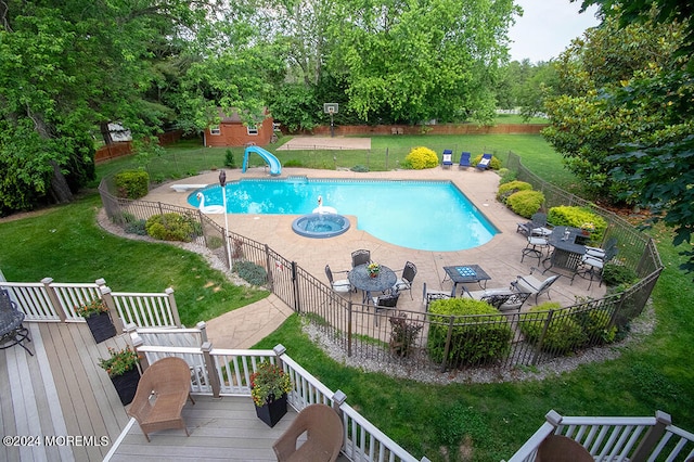 view of swimming pool with fence, a water slide, a wooden deck, a fenced in pool, and a lawn