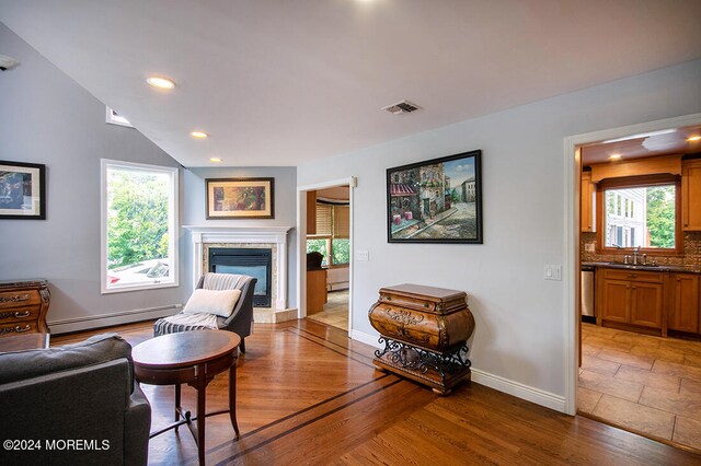 living room featuring visible vents, a glass covered fireplace, baseboards, baseboard heating, and recessed lighting