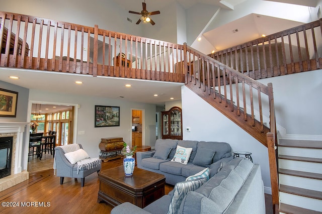 living area featuring recessed lighting, a ceiling fan, a towering ceiling, and wood finished floors