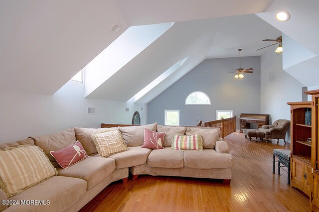 living area featuring a skylight, a ceiling fan, light wood-style flooring, and visible vents