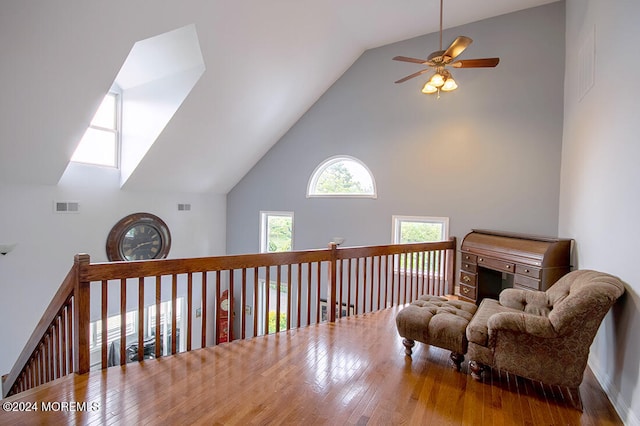 sitting room with a ceiling fan, high vaulted ceiling, visible vents, and wood finished floors