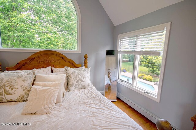 bedroom featuring light wood-style floors, vaulted ceiling, and baseboard heating