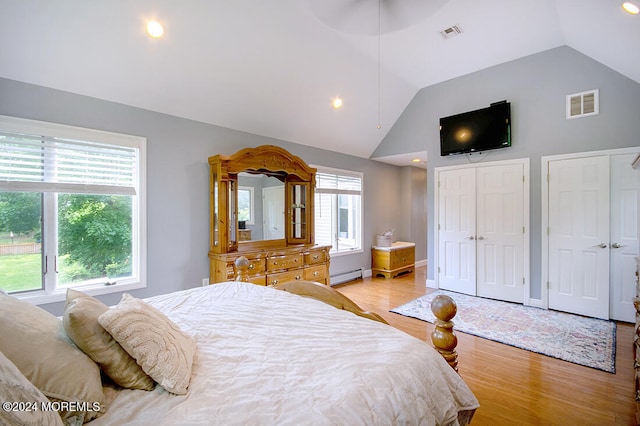 bedroom with a baseboard radiator, vaulted ceiling, light wood-type flooring, and visible vents