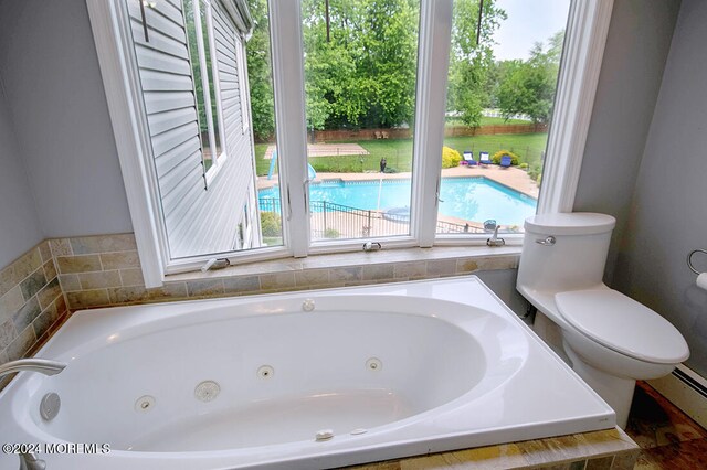 bathroom with a jetted tub, a baseboard radiator, and toilet