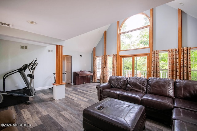living area with high vaulted ceiling, a wealth of natural light, dark wood-type flooring, and visible vents