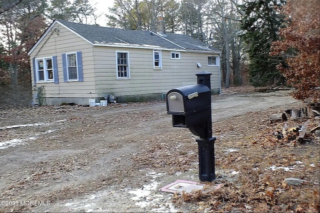 view of side of home with a shingled roof and a chimney