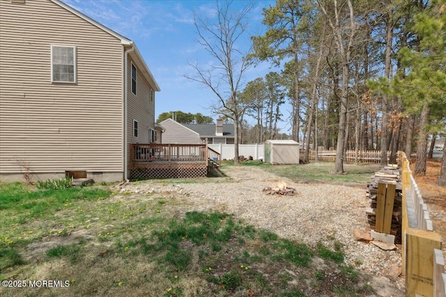 view of yard featuring a deck, fence, an outdoor structure, a shed, and an outdoor fire pit