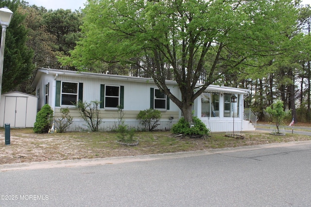 manufactured / mobile home featuring a sunroom, a shed, and an outbuilding