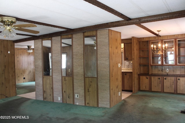 interior space with ceiling fan with notable chandelier, beam ceiling, and wooden walls