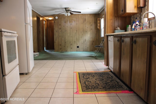 kitchen featuring ceiling fan, light colored carpet, wood walls, light tile patterned floors, and freestanding refrigerator