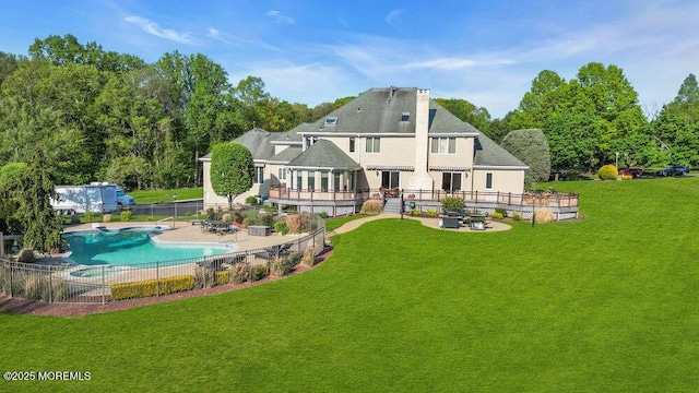 rear view of house featuring a fenced in pool, a lawn, fence, and a patio