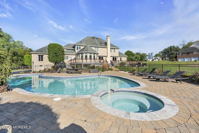 view of swimming pool featuring a pool with connected hot tub, fence, and a patio area