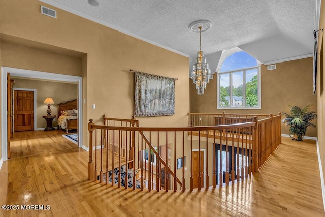 hall with visible vents, wood finished floors, and an upstairs landing