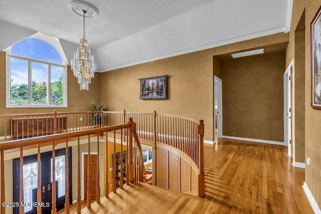 stairs with a textured ceiling, visible vents, vaulted ceiling, wood-type flooring, and a chandelier
