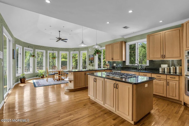 kitchen featuring visible vents, a kitchen island, light wood-style floors, tasteful backsplash, and stainless steel appliances