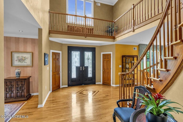 foyer with french doors, a towering ceiling, wood finished floors, stairway, and baseboards