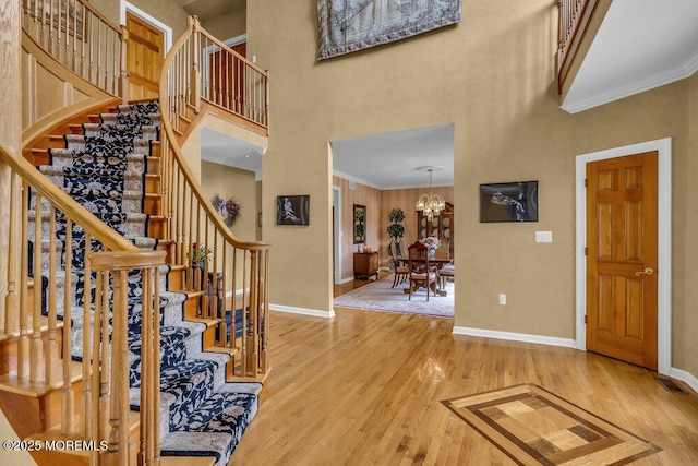 entryway with light wood-style floors, baseboards, a high ceiling, and crown molding