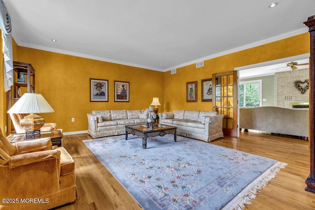 living area featuring baseboards, ornamental molding, wood finished floors, and visible vents