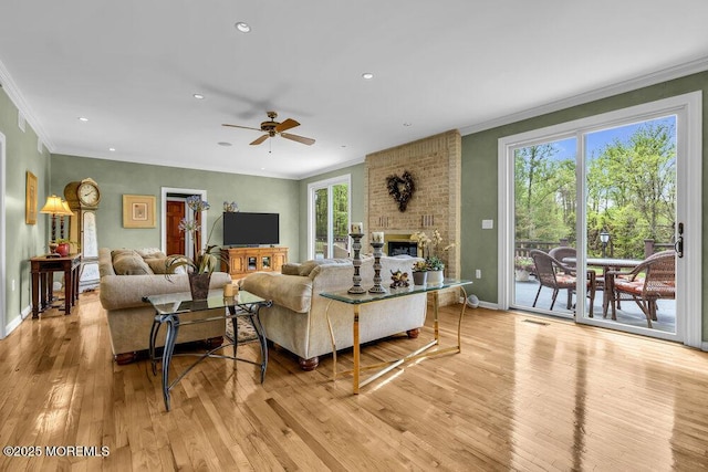 living area with crown molding, baseboards, ceiling fan, and light wood-style floors