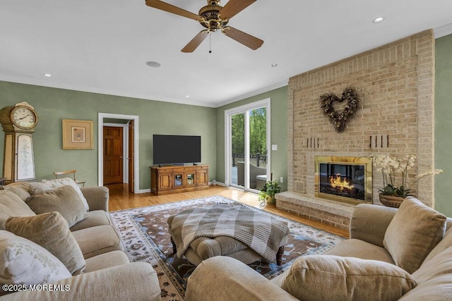 living room featuring crown molding, ceiling fan, a brick fireplace, recessed lighting, and wood finished floors