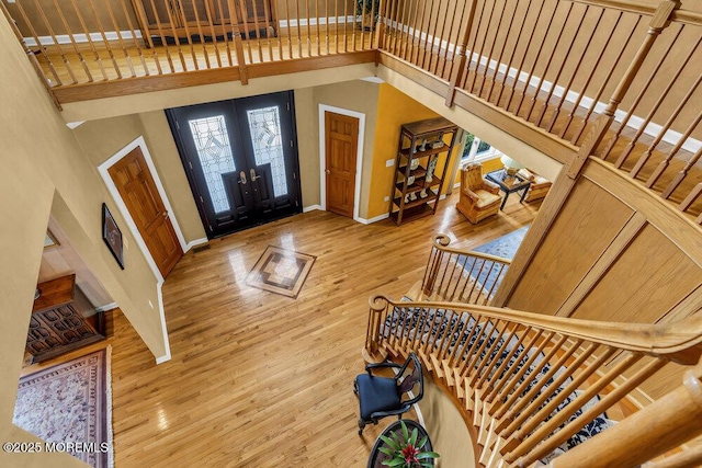 foyer featuring french doors, wood finished floors, stairway, baseboards, and a high ceiling