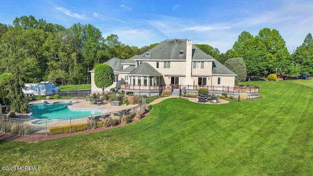 back of house with a chimney, fence, a fenced in pool, a yard, and a patio